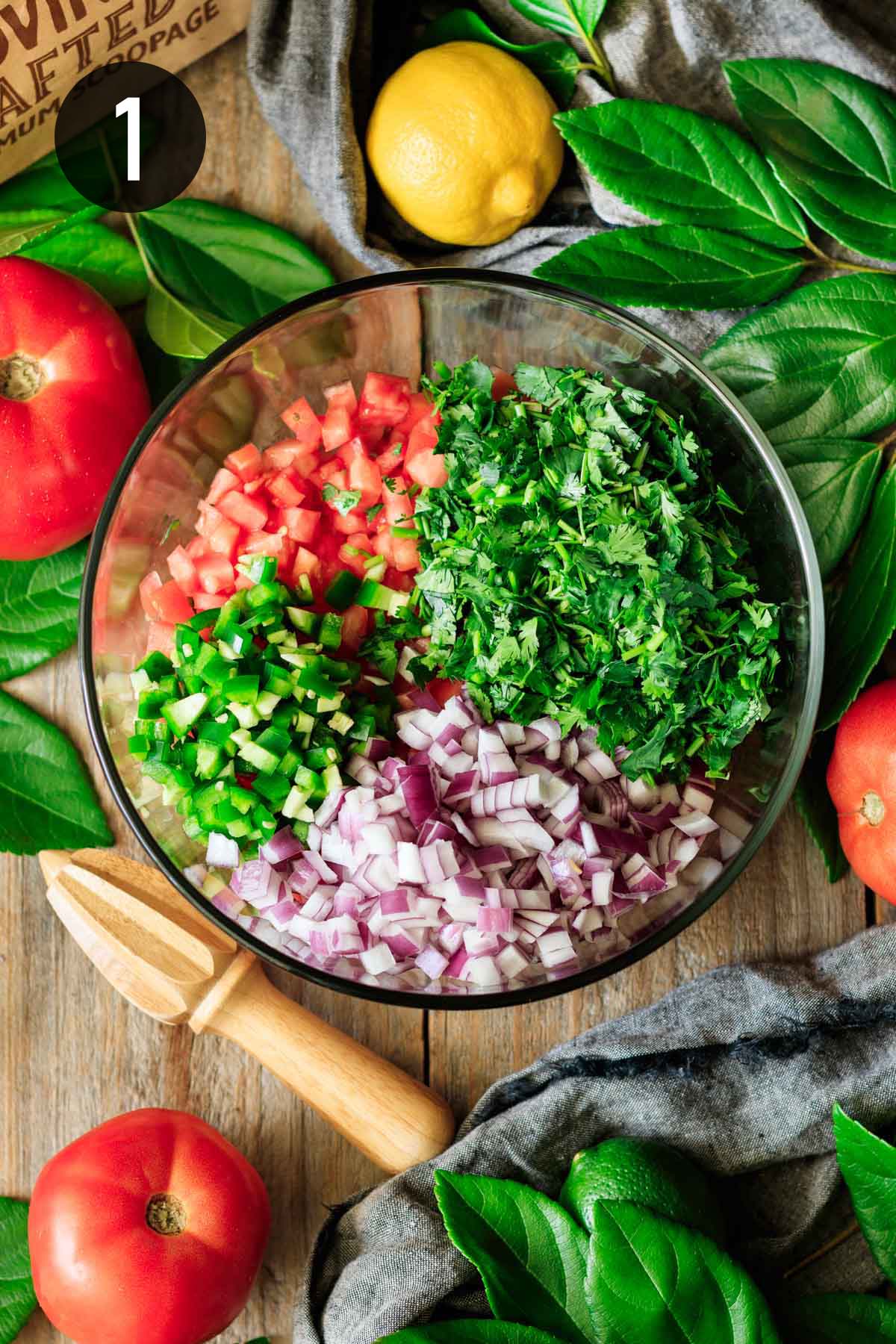 bowl of chopped veggies and cilantro in a glass bowl.
