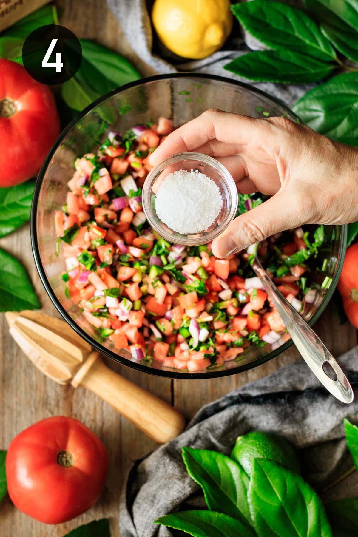 adding salt to the tomato salsa.