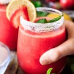 person holding a glass of frozen strawberry lemonade.