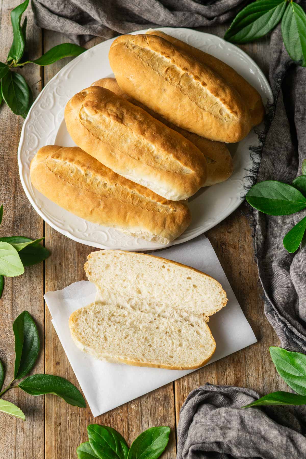 platter of hoagie rolls with a roll cut open and laid on a piece of parchment.