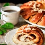 slice of Swedish tea ring on a plate with a cup of coffee.