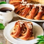 slice of Swedish tea ring on a plate with a cup of coffee.