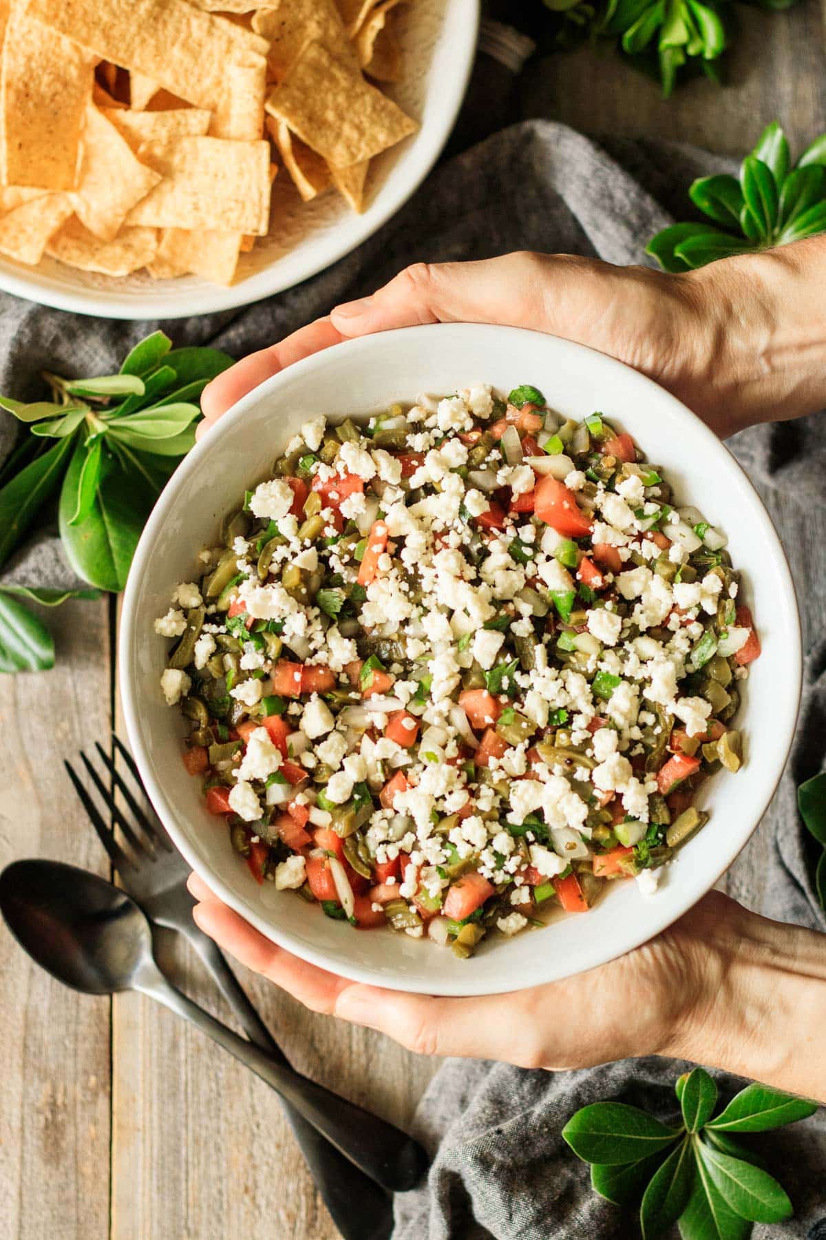 holding a white bowl of nopales salad.
