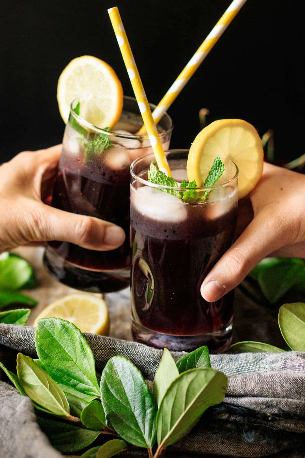 people doing a toast with two glasses of cherry lemonade.