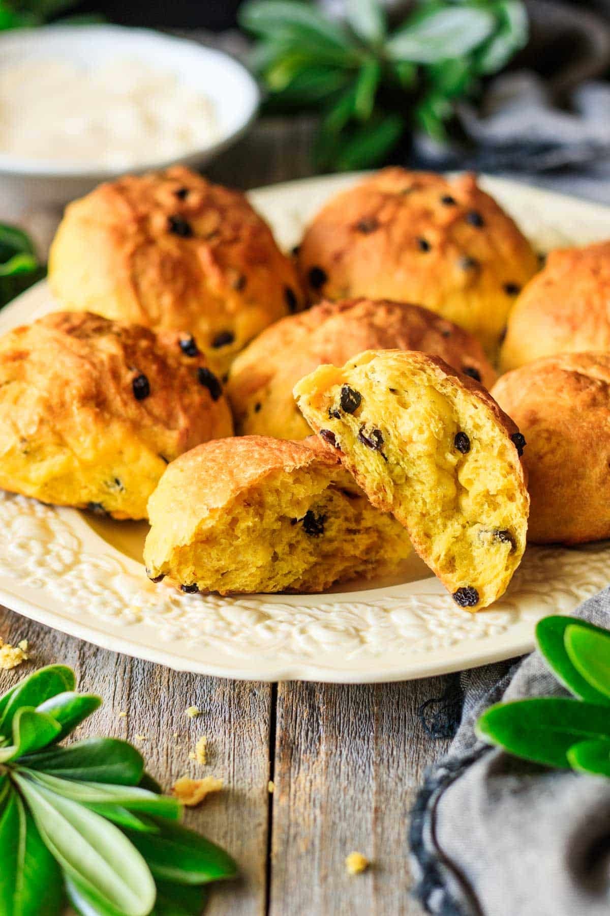 Cornish saffron bun torn in half crosswise on a platter with other buns.