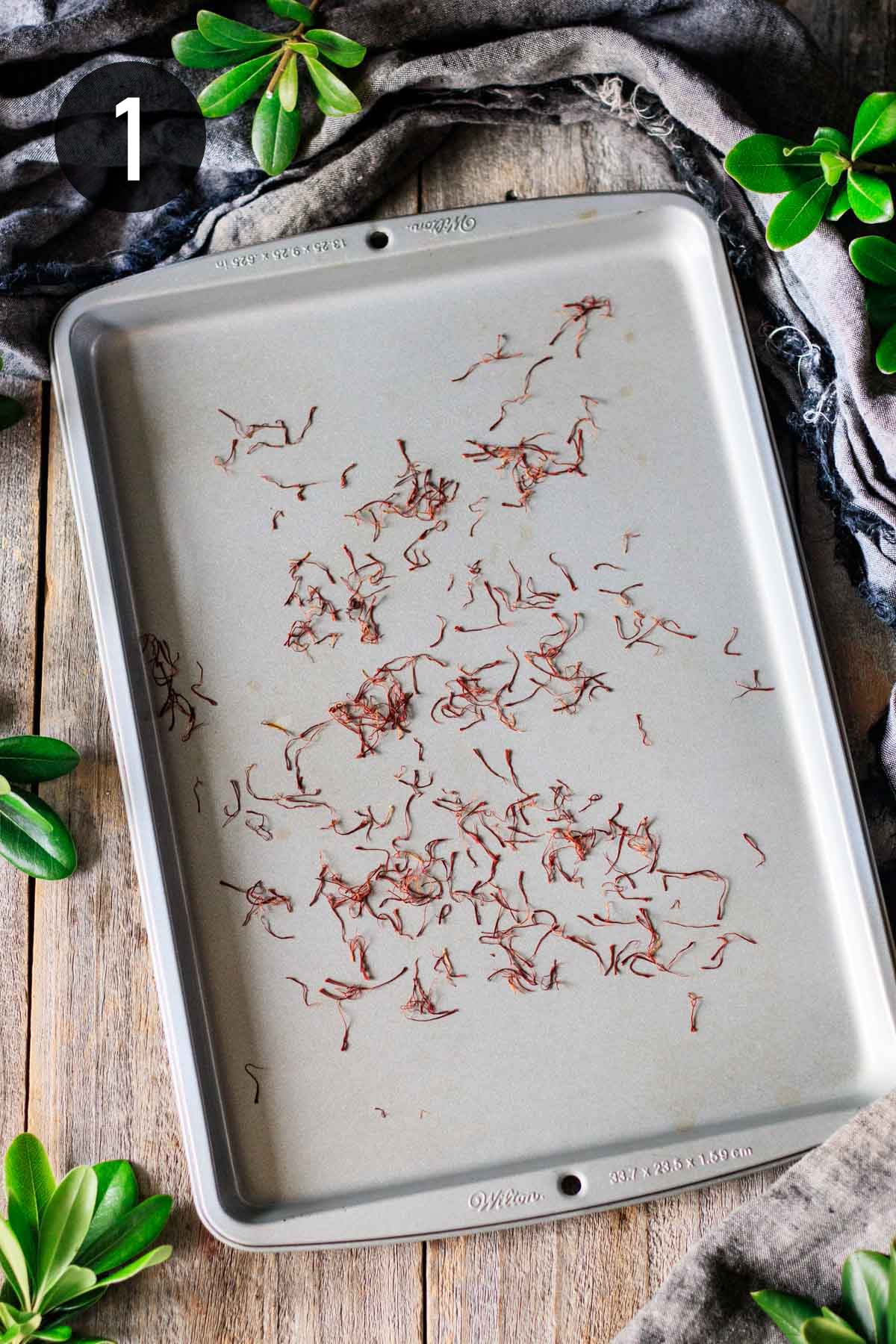 dark red saffron threads toasted on a small cookie sheet.
