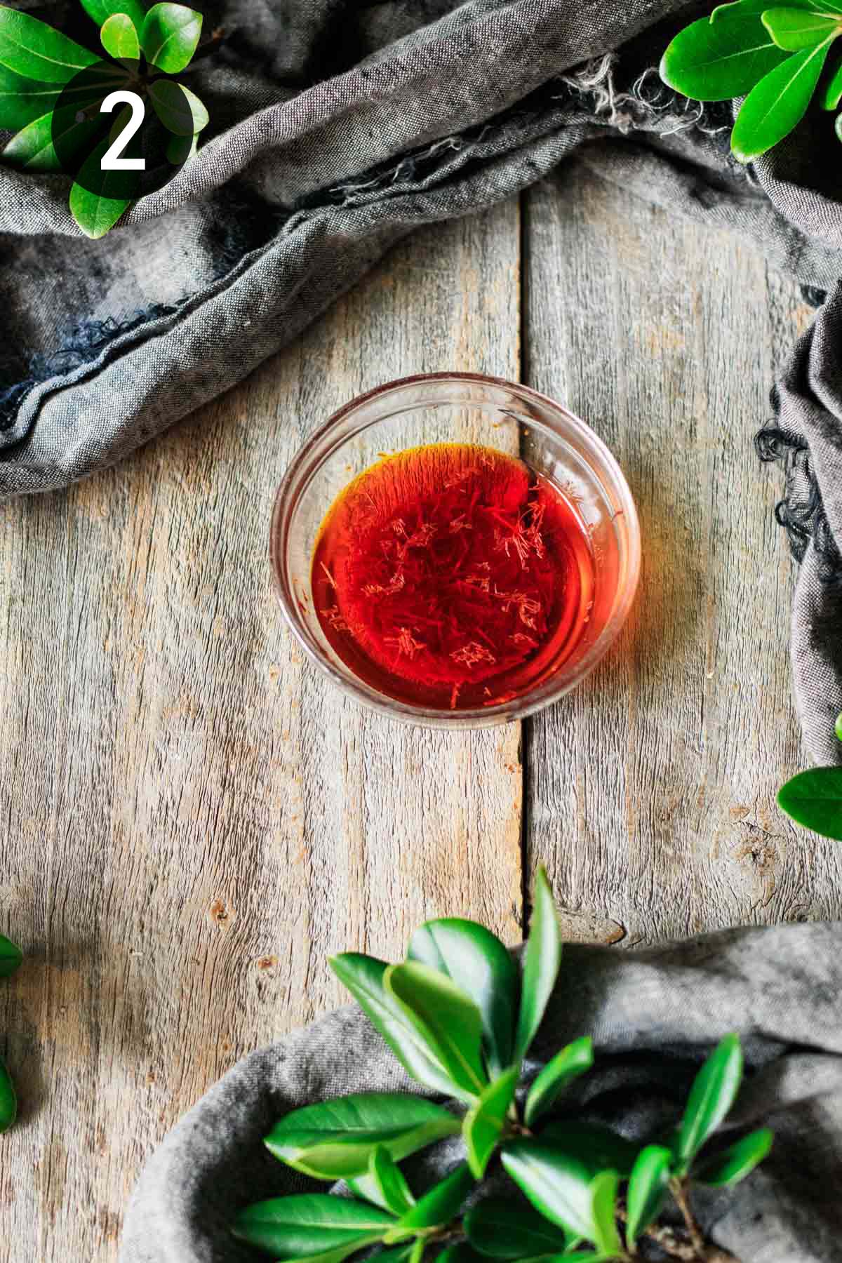 deep orange infused saffron liquid in a small glass bowl.