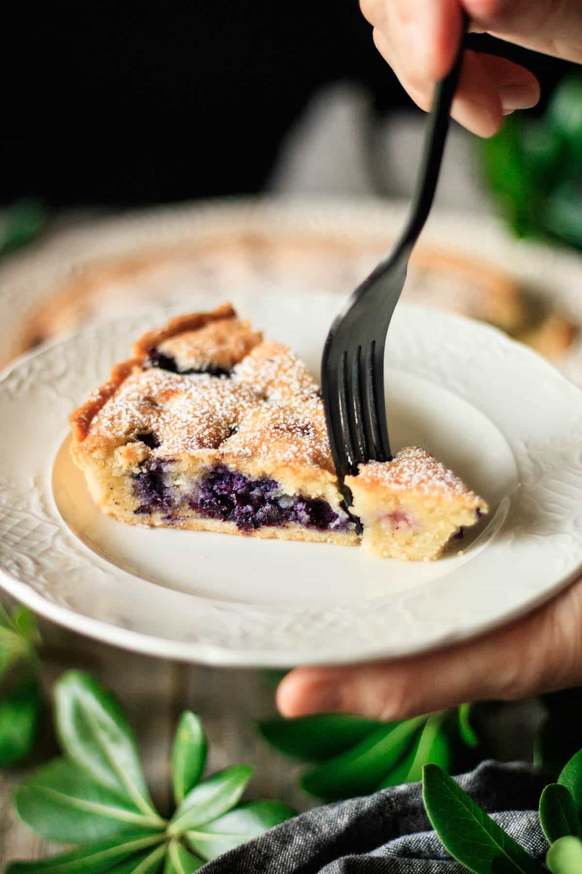 person taking a forkful of blueberry frangipane tart.