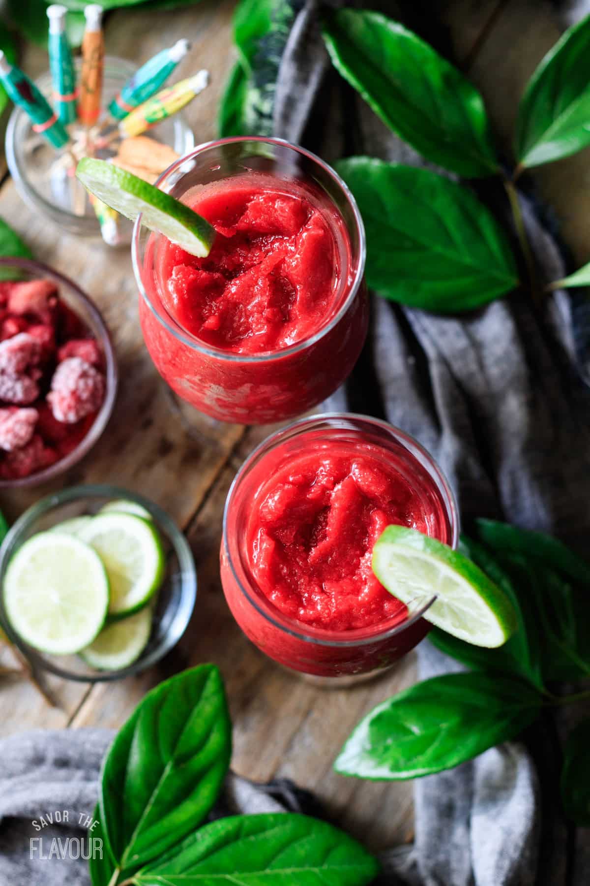 two glasses of raspberry daiquiri with a glass of mini umbrellas.