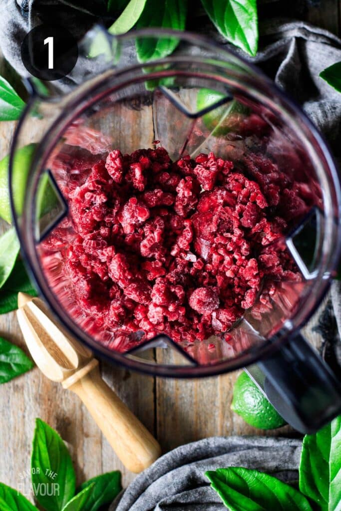 adding frozen raspberries to a blender.