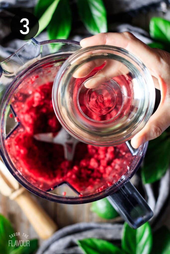adding simple syrup to the frozen raspberries.
