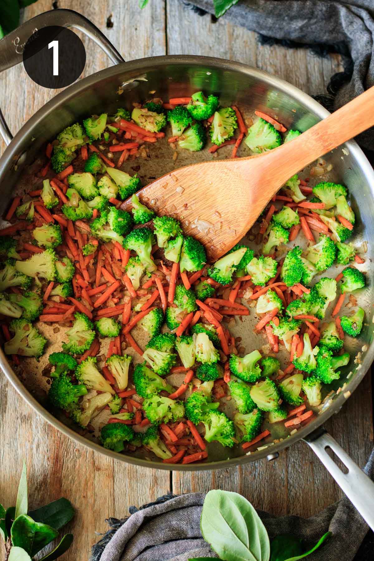 cooking julienned carrots and broccoli florets in a skillet.