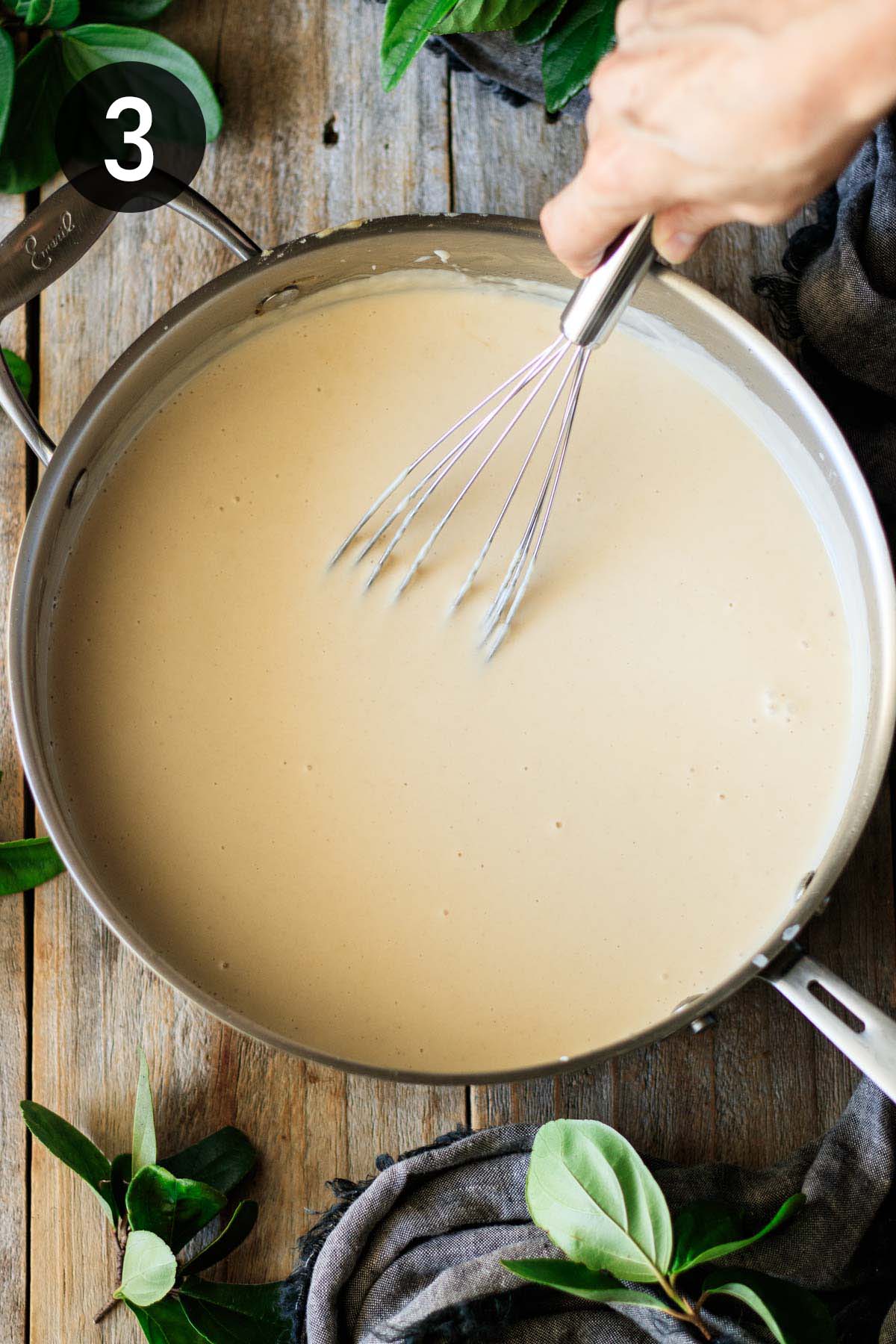 whisking white sauce in a skillet.
