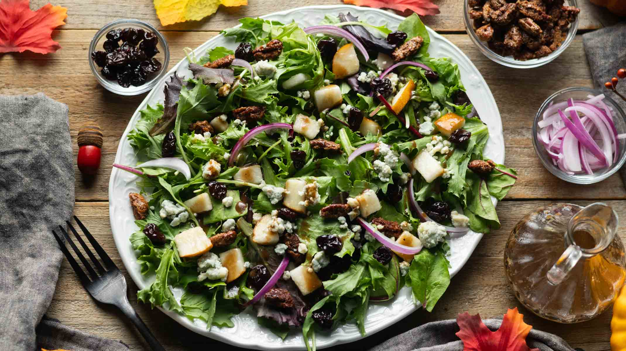 white platter of fall harvest salad with bowls of toppings.